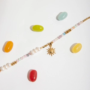 Colorful gemstone and pearl necklace with golden sun pendant on a clean white backdrop