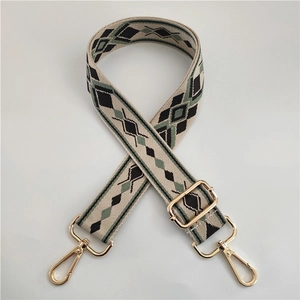 Detail of adjustable wide bag strap with beige geometric pattern and gold metal hooks
