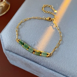 Détail d'un bracelet en chaîne dorée ajustable avec cinq pierres vertes cubiques