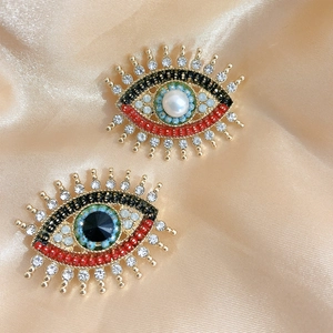 Vintage evil eye brooches with freshwater pearls and colorful beads on champagne silk cloth