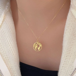 Close-up of gold 925 silver necklace featuring a hollow world map globe pendant on model