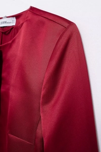 Detail of elegant dark red satin top showing neckline stitching and BOWWOMAN brand label