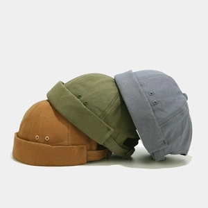 Detailed stack of three canvas docker hats in caramel, army green, and blue-gray hues