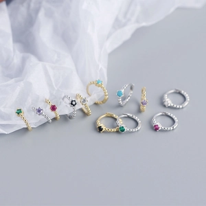 Macro view of multi-color zircon silver hoop earrings in gold and silver finishes