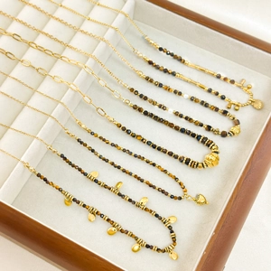 Faceted natural tiger eye necklace with gold heart pendants on a jewelry display tray