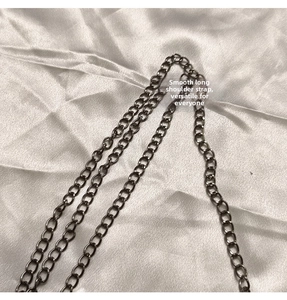 Detail of high-quality dark grey metal chain strap on soft pleated fabric background