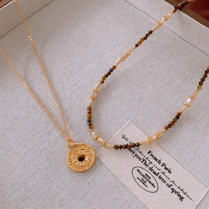 Flat lay of vintage gold plated compass necklace with tiger eye stone and beaded chain