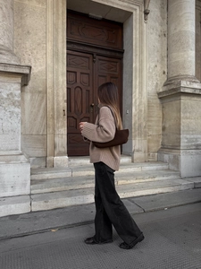 Close-up of a turtleneck knit sweater paired with a dark brown shoulder bag and denim