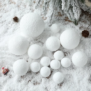 White Christmas foam snowballs in various sizes on artificial snow with festive decor