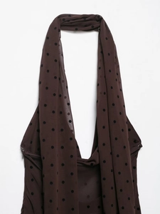 Detail view of dark brown polka dot mesh fabric on a backless halter neck dress