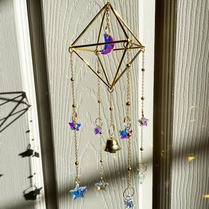 Attrape-soleil doré avec lune mauve et prismes en cristal projetant un arc-en-ciel