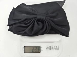 Detail showing the lightweight 23.3g design of the black satin oversized bow hair clip