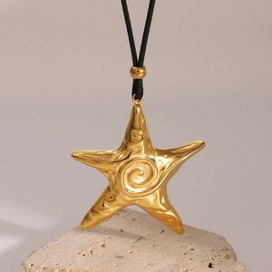 Macro shot of 18k gold plated starfish pendant with black wax cord on a textured stone