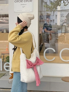 Close-up of white lamb wool tote bag with a red checkered bow on the front