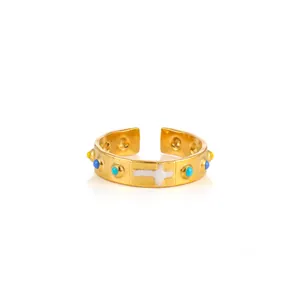 Detail of adjustable gold ring with white cross and colorful enamel bead accents