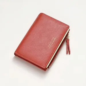 Detail view of brick red short fold wallet with pebbled texture and gold zipper