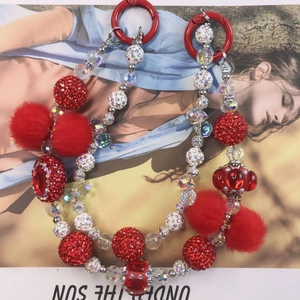 Detail of handmade beaded phone strap with red plush balls and rhinestone charms