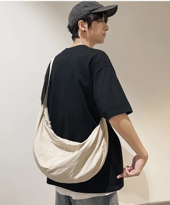 Détail d'un sac demi-lune en nylon beige avec bandoulière réglable sur un mannequin