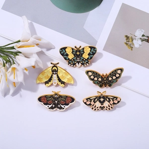 Detailed view of five vintage butterfly enamel pins with moon and floral patterns