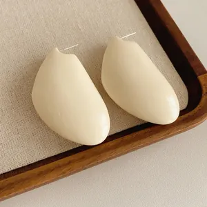 Elegant geometric cream resin earrings with silver needle on a vintage wood tray