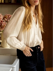 Detailed view of elegant white shirt showing intricate lace cuffs and pearl buttons