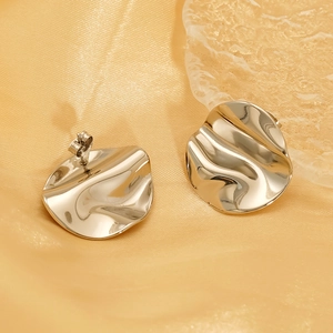 Minimalist wavy irregular gold earrings with textured metallic finish on silk background