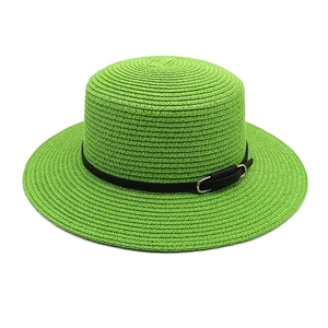 Gros plan détaillé d'un chapeau de paille vert vif avec sangle noire et boucle argentée