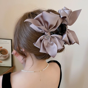 Close-up of a large grey satin bow hair claw with sparkling rhinestone on a model's hair
