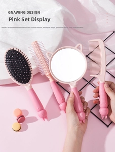 Close-up of pink handheld mirror and hairbrush set with cute cat ear design and relief