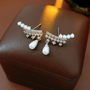 Macro shot of silver drop earrings with white pearls and sparkling cubic zirconia stones