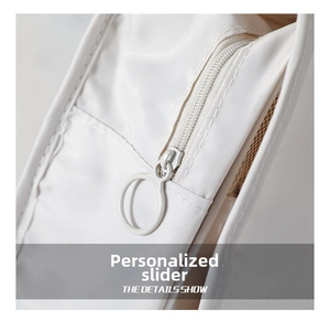 Detail of white toiletry bag showing a large circular metal zipper pull and mesh pocket