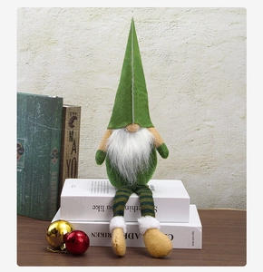 Detail of green Christmas gnome with long striped legs and white beard on white books