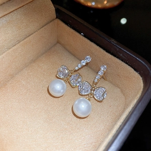 Détail des boucles d'oreilles cœur en zircon et perles sur une boîte à bijoux en velours