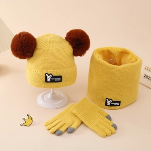Close-up of yellow knit winter set for kids featuring soft pom-poms and rabbit tags
