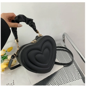Detail of black heart-shaped PU leather handbag with quilted texture and ruched handle
