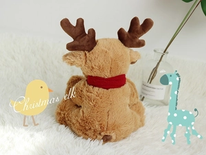 Rear view of Christmas reindeer plush toy with red scarf on soft white carpet