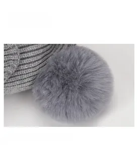 Detailed macro view of a large faux fur pom-pom on top of a grey ribbed knit infant hat