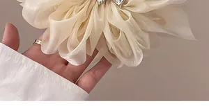 Detail der eleganten cremefarbenen Chiffon-Blumen-Haarklammer mit funkelndem Strassstein