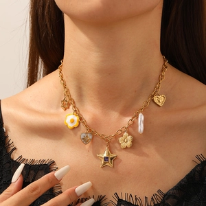 Gold-tone multi-charm necklace with star, pearl, and floral pendants worn by a model