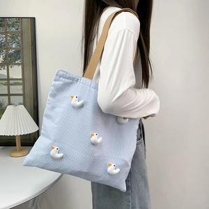 Detail of blue striped canvas tote bag with cute 3D duck dolls and khaki straps