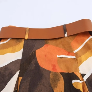 Detail van een bruine riem op een popeline jurk met kleurrijke geometrische print