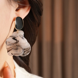 Close-up of elegant marble pattern flower earrings worn on ear with gold accents