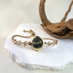 Detail of vintage gold bracelet watch with crystal leaf links on white stone