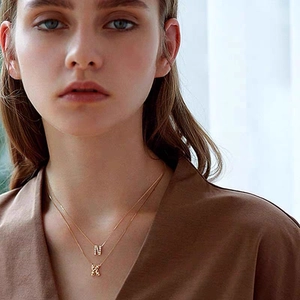 Collana in titanio placcato oro 18K con pendenti a lettere N e K con piccoli cristalli