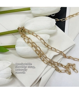 Detailed macro shot of a golden metal chain strap on white fabric with elegant tulips
