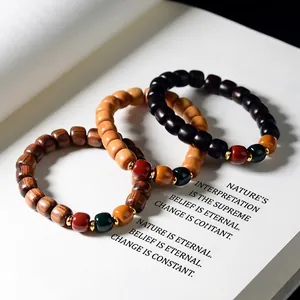 Close-up of sandalwood beads with red, green, and orange charms on an ancient book
