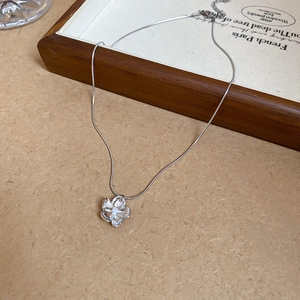 Close-up of silver flower pendant necklace with pearl center on wood display surface