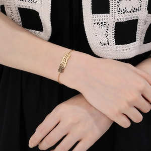 Nahaufnahme eines goldenen MAMA-Armbands mit Kristallen am Handgelenk