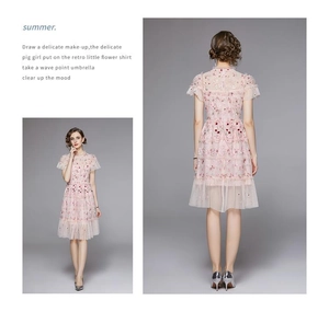 Détails de la robe en tulle rose avec broderies florales rouges et des paillettes