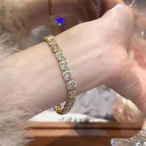 Détail d'un bracelet doré avec zircons carrés porté sur une manche en peluche